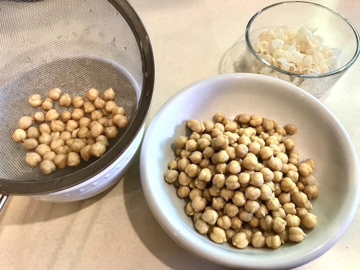 This is a photo of three bowls showing an example of how to take shins off of cooked chickpeas.